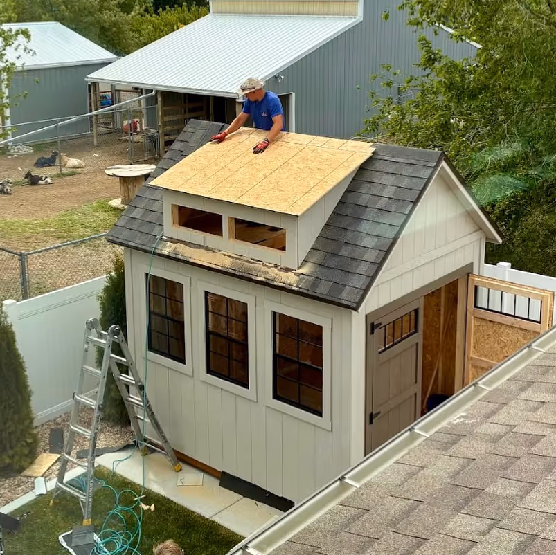 An Apex Shed Company craftsman installing a dormer on a custom storage shed during on-site construction